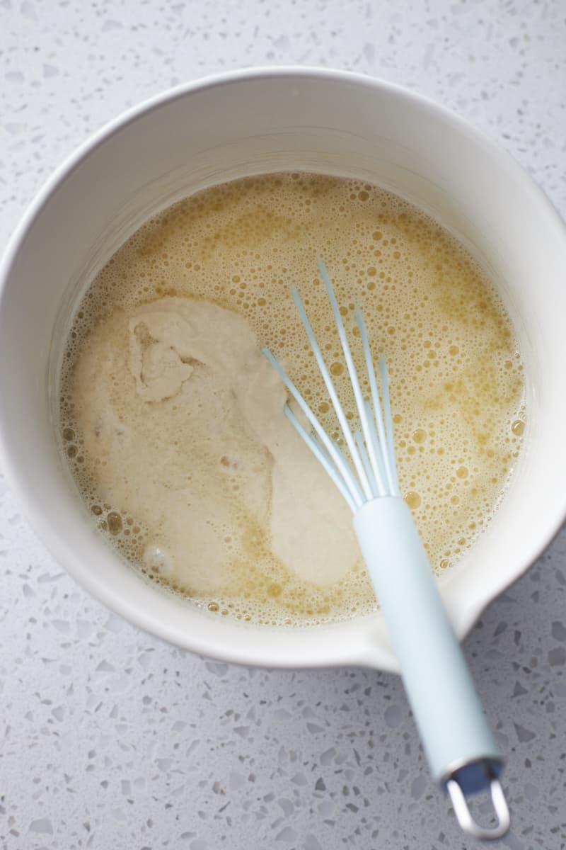 Liquid ingredients in a large white bowl with a whisk.