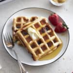 Closeup of two waffles on a white plate with a fork.