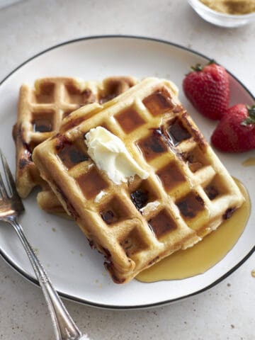 Closeup of two waffles on a white plate with a fork.