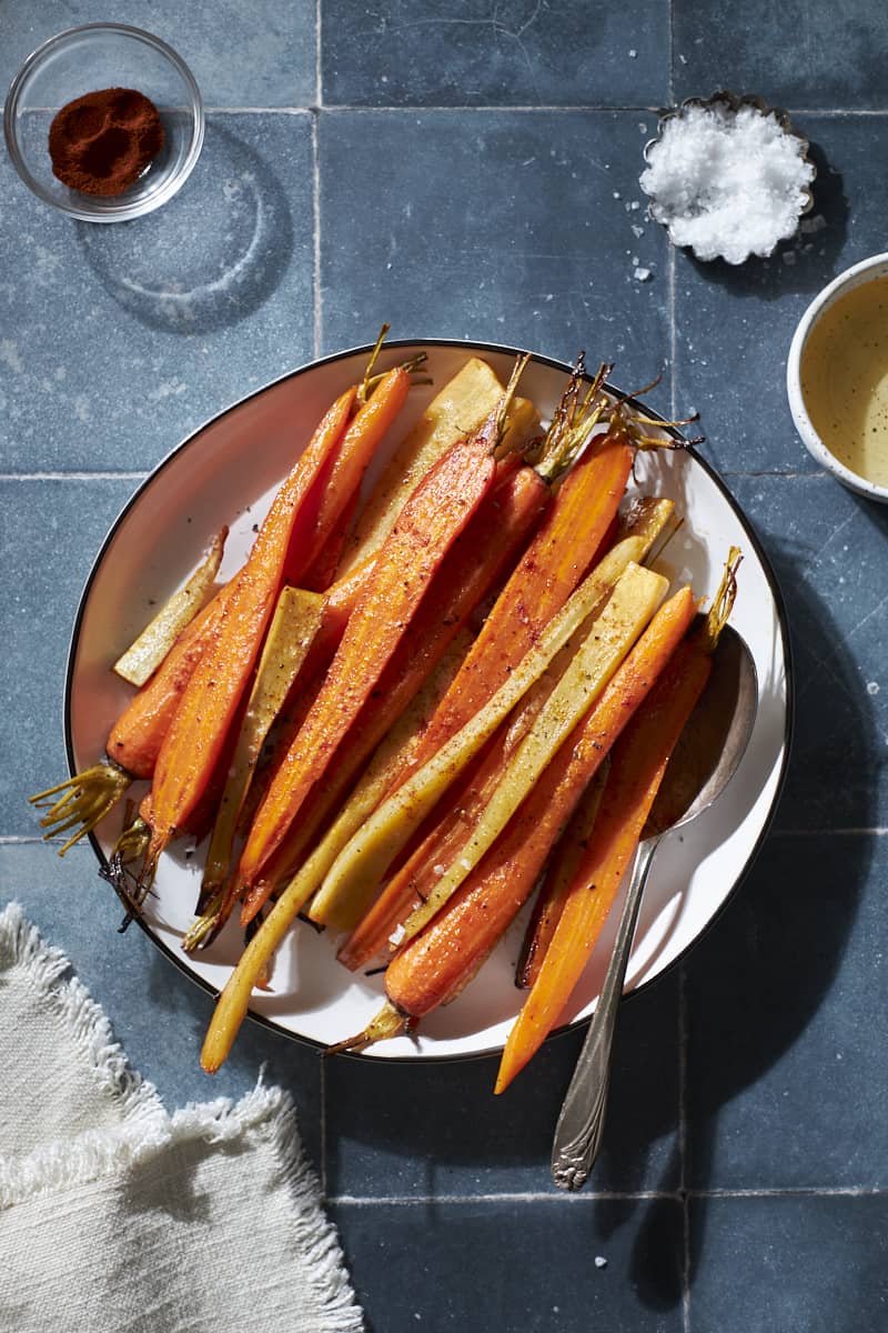 Overhead view of roasted carrots and parsnips on a white platter.