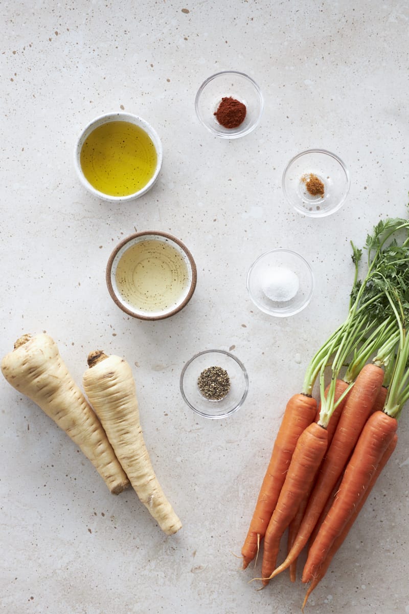 Ingredients for honey roasted carrots and parsnips in small bowls.