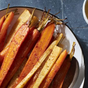 Honey roasted carrots and parsnips on a white platter.
