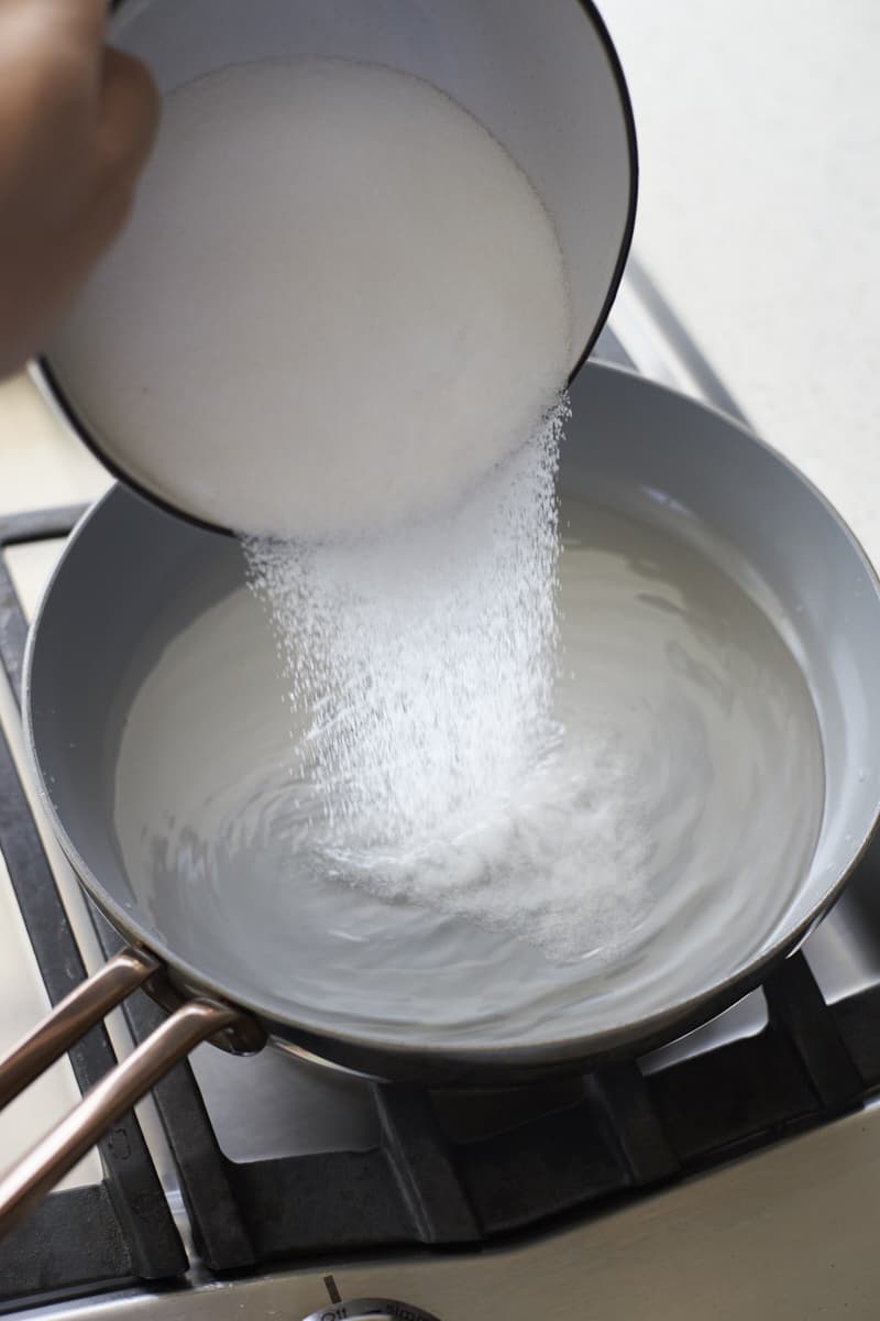 Sugar being added to water in a small skillet.