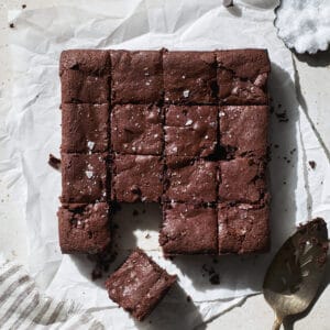 Sourdough discard brownies cut into squares on white parchment paper.