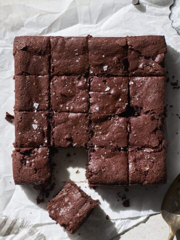 Sourdough discard brownies cut into squares on white parchment paper.