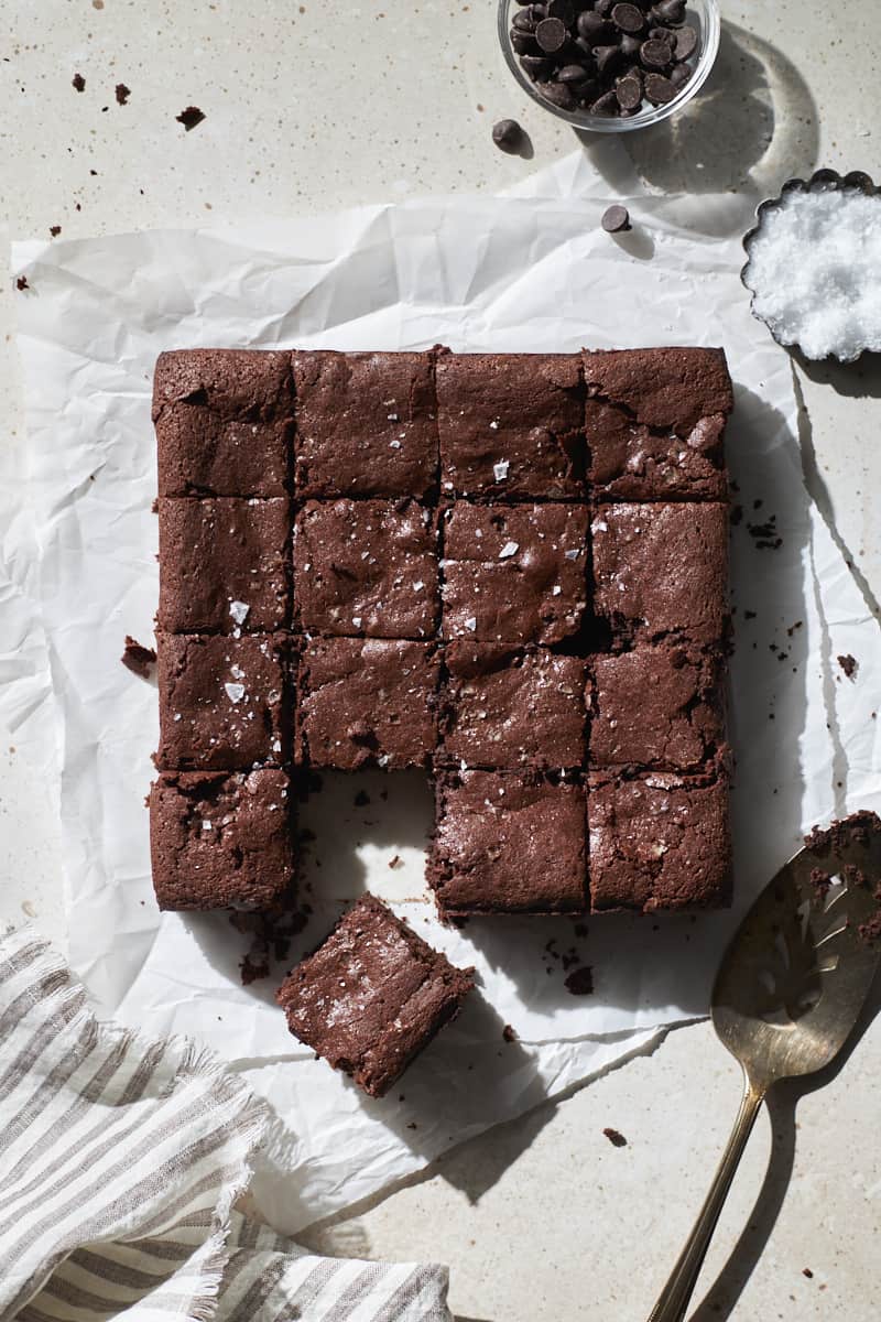 Sourdough discard brownies cut into squares on white parchment paper.