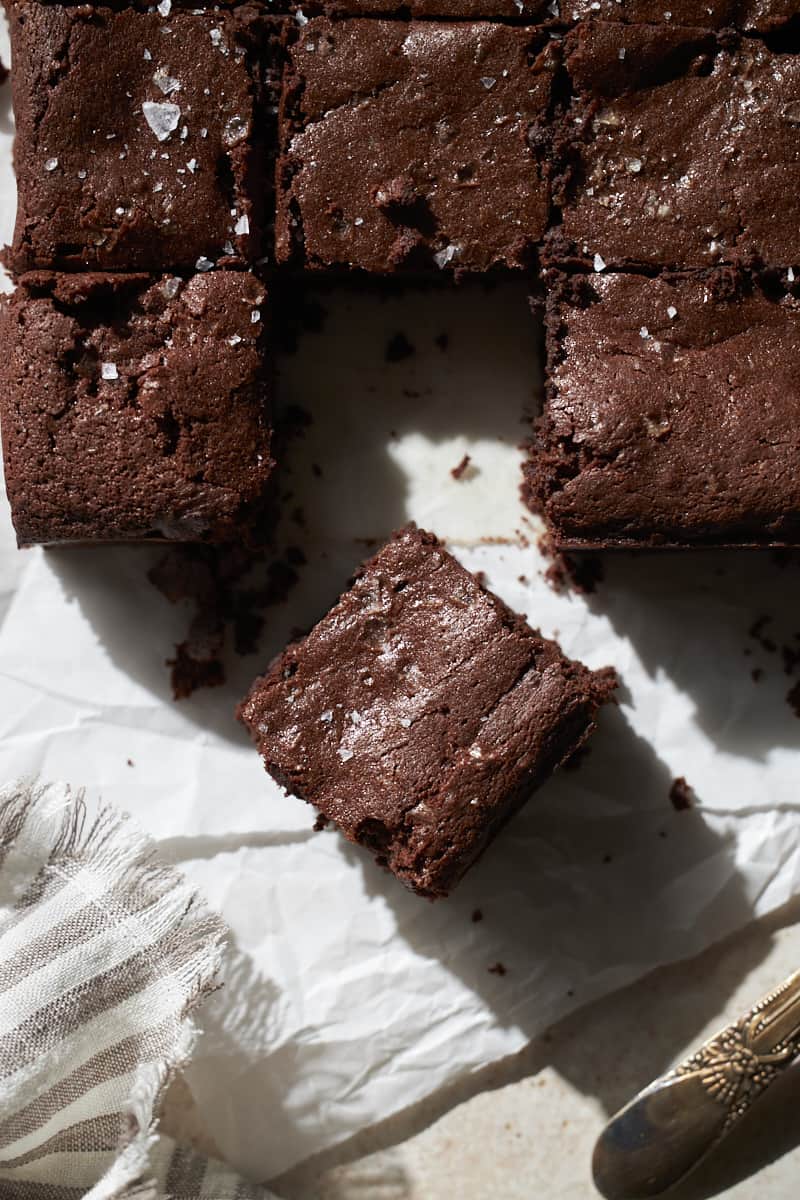 One brownie separated from the rest on a piece of white parchment paper.