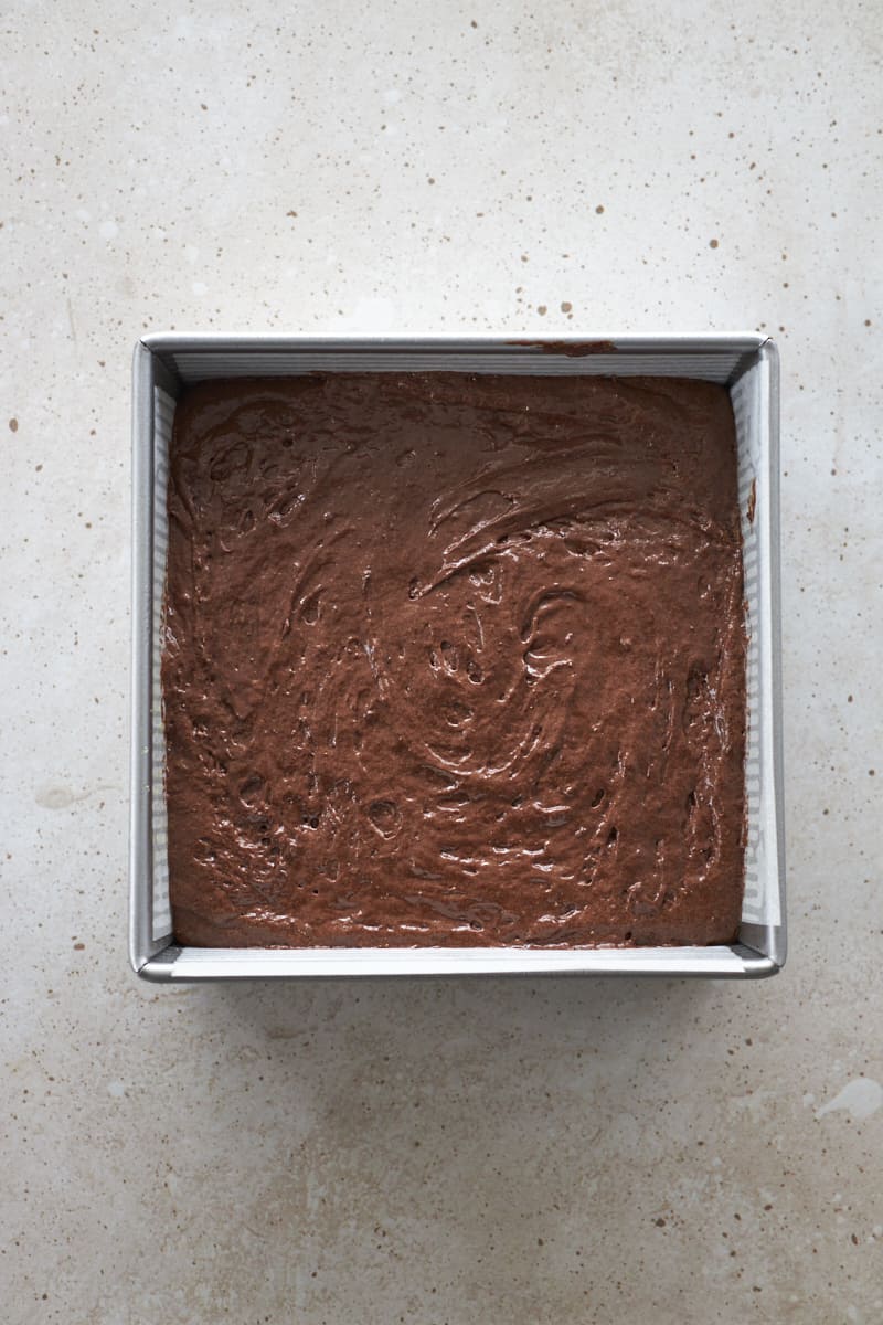 Brownie batter in a square metal baking pan.