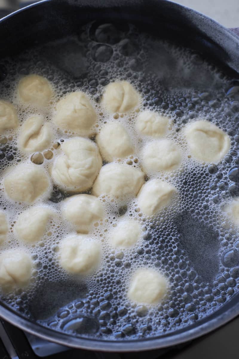 Pretzel bites boiling in a large pot.