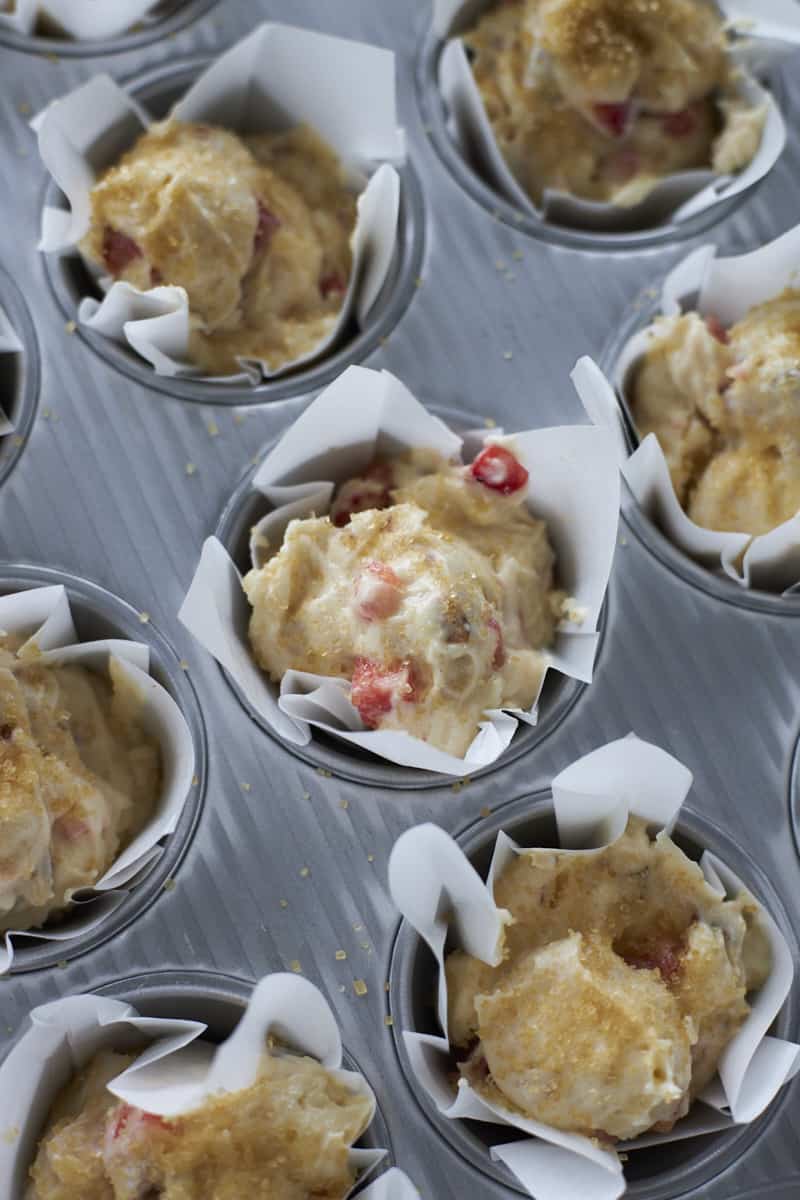 Batter in white muffin liners in a muffin tin.