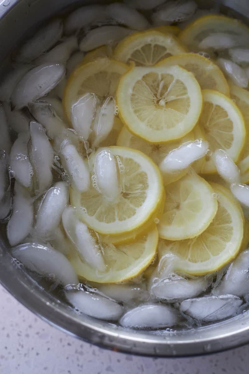 Lemon slices in a large bowl of ice water.