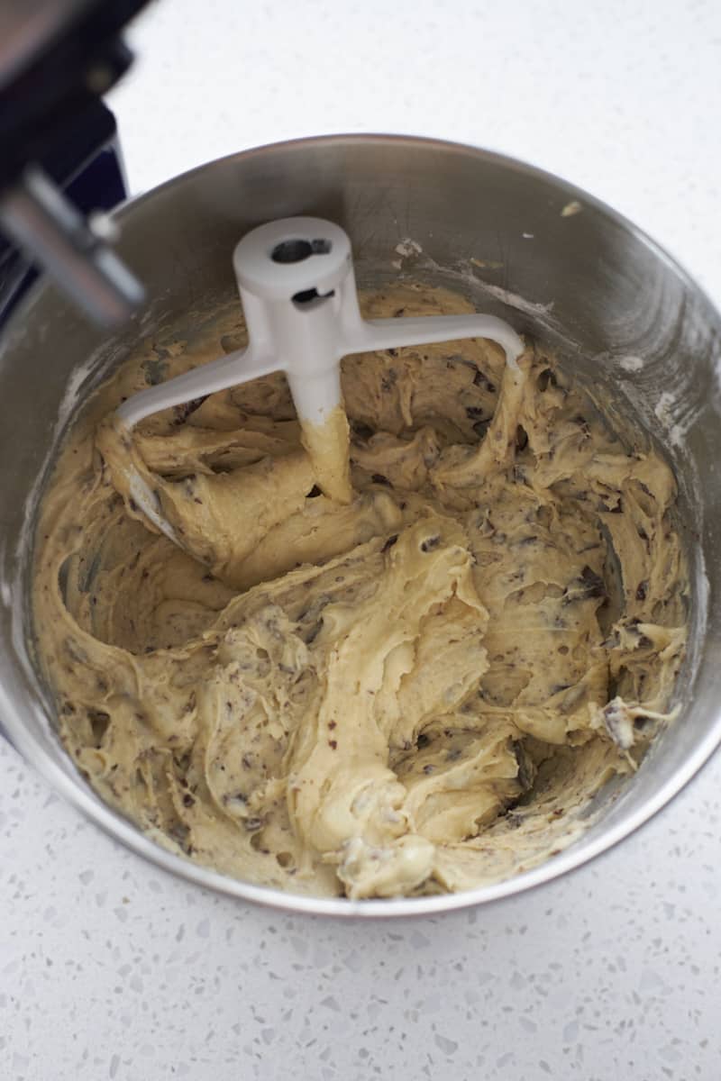 Dough with chocolate chips in the bowl of a stand mixer.