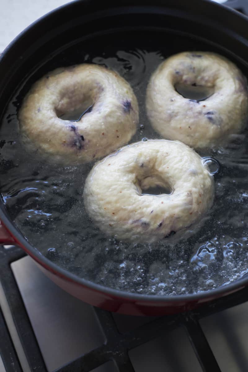 Bagels boiling in a pot of water.