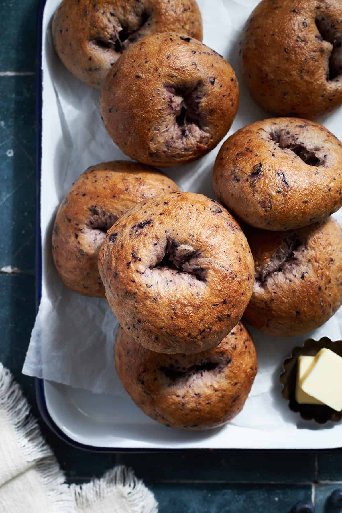 Sourdough Discard Blueberry Bagels in a pile on a white tray.