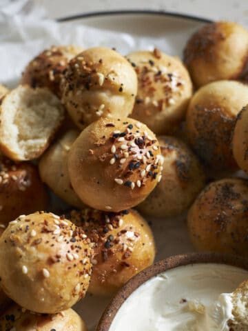 Sourdough discard bagel bites on a plate with cream cheese.