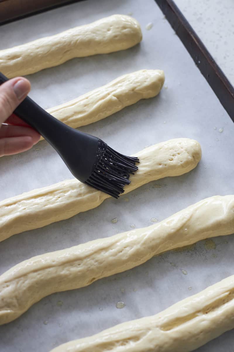 Brushing breadsticks with melted butter.