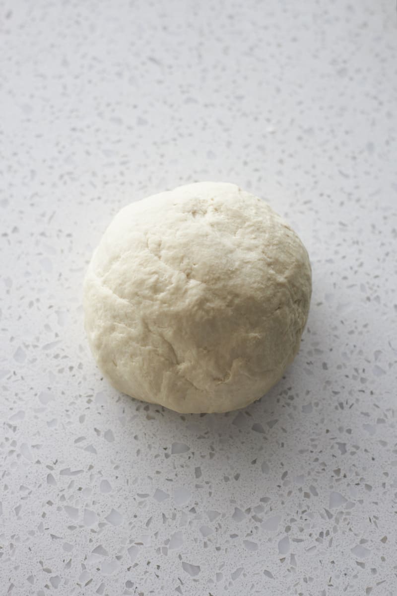 Dough in a ball on a work surface.