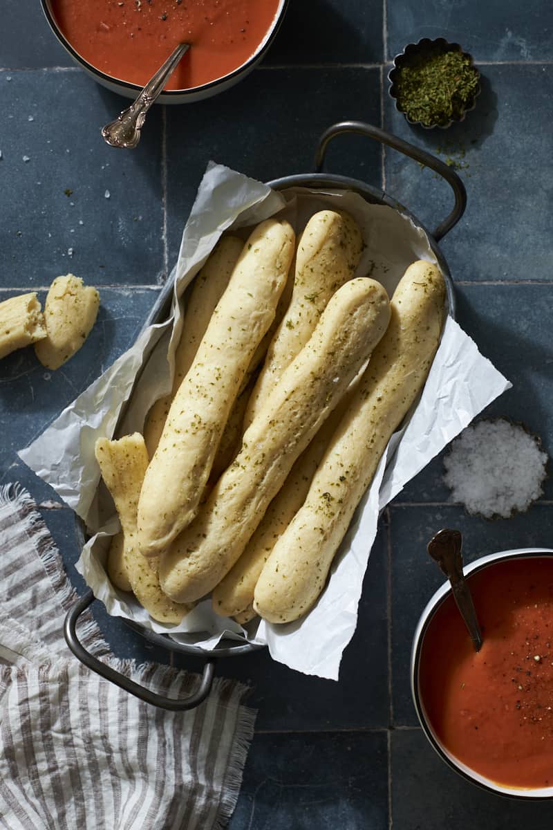 Sourdough discard breadsticks in a tray with two bowls of tomato soup.