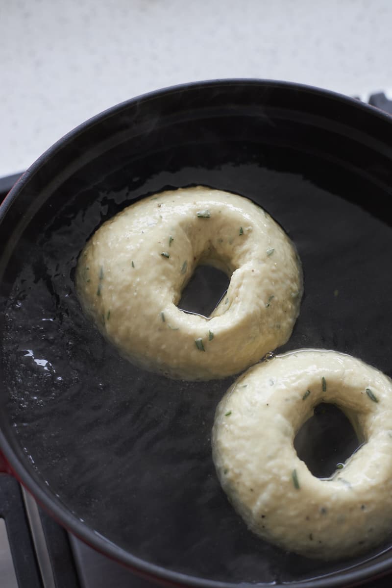 Bagels boiling in a pot of water.