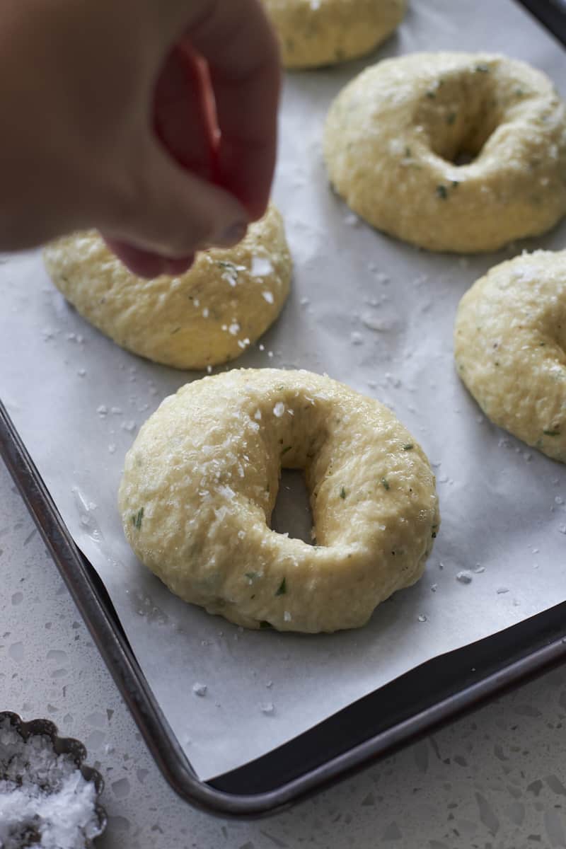 Bagels being sprinkled with sea salt.