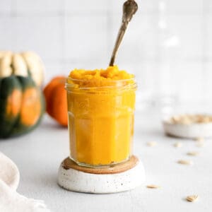 Homemade pumpkin purée in a jar with a spoon.