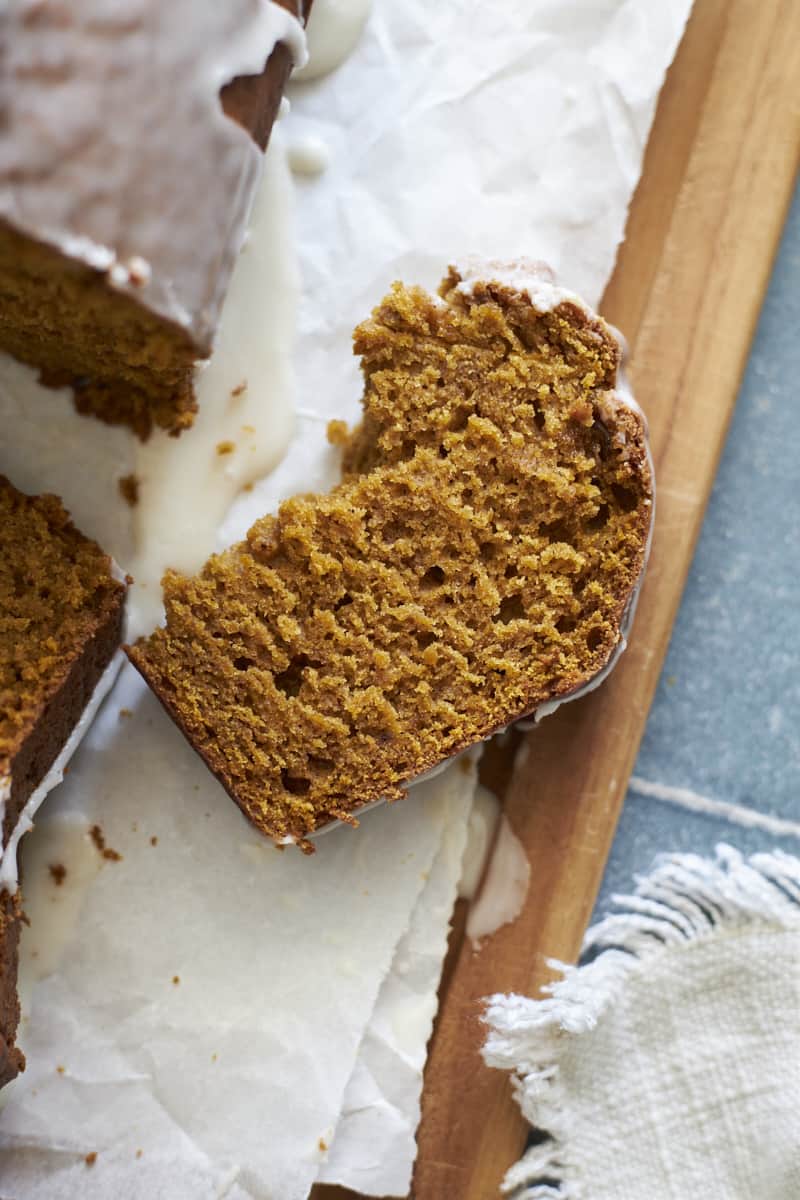 Torn half piece of Sourdough Discard Pumpkin Bread on a wooden cutting board.