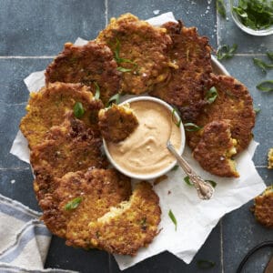 Zucchini and Sweetcorn Fritters on a platter with aioli dipping sauce.