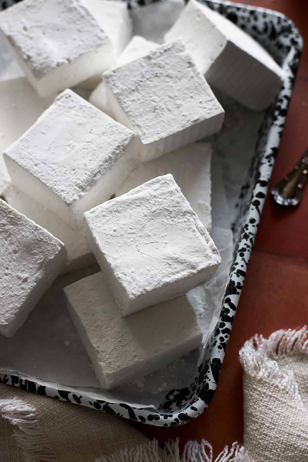 White marshmallows in a pile on a black and white tray.