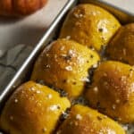 Closeup of Sourdough Discard Pumpkin Dinner Rolls in a baking pan.