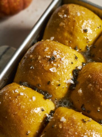 Closeup of Sourdough Discard Pumpkin Dinner Rolls in a baking pan.