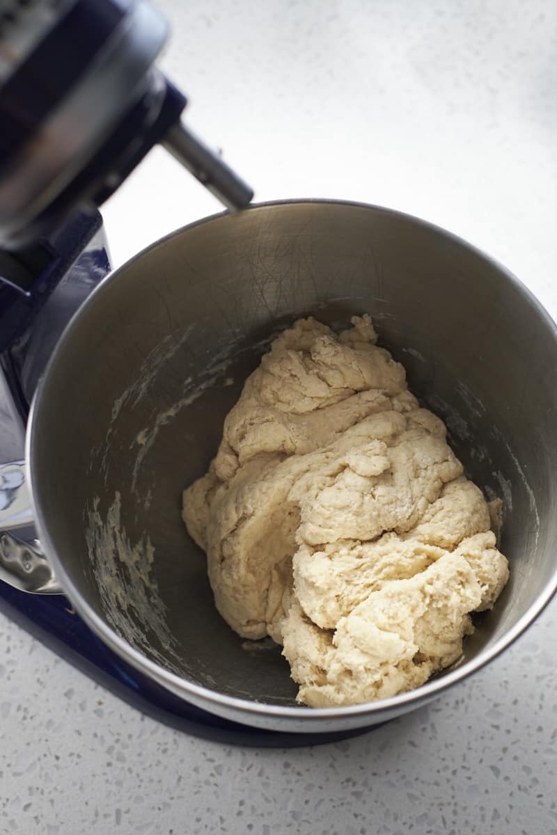 Shaggy dough in the bowl of a stand mixer.