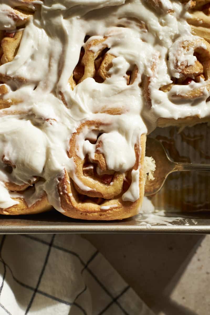 Overhead view of Sourdough Discard Apple Cinnamon Rolls with frosting in the baking pan with the serving scoop.