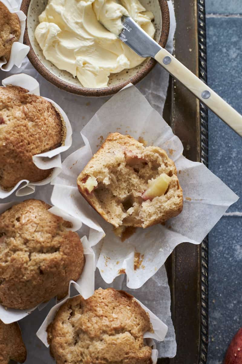 Overhead view of a halved Sourdough Discard Apple Muffin on white parchment paper.