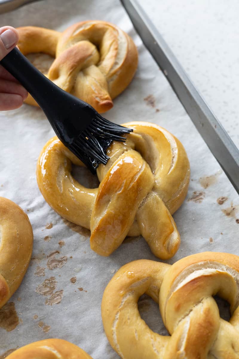 Pretzels being brushed with melted butter. 