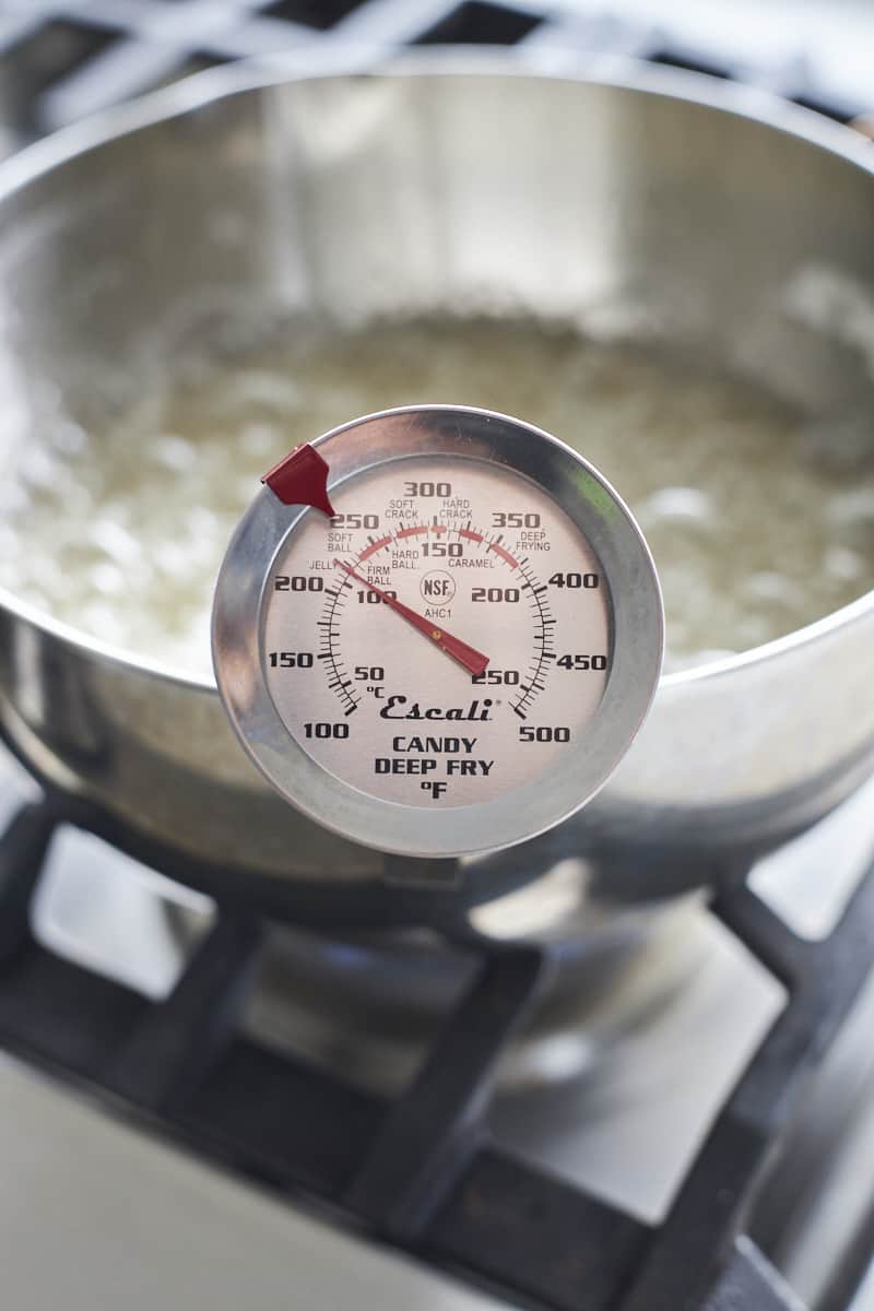 A candy thermometer on the edge of a pan.