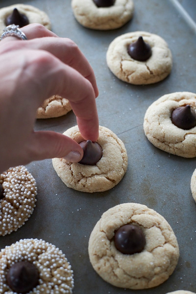 A hand putting the Hershey's Kiss on top of the cookie.