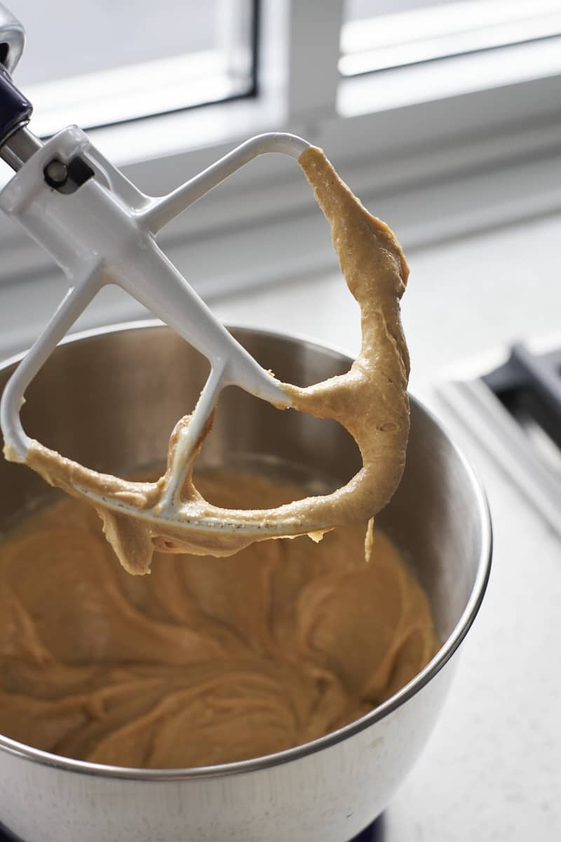 Sugars and wet ingredients mixed in the bowl of a stand mixer.