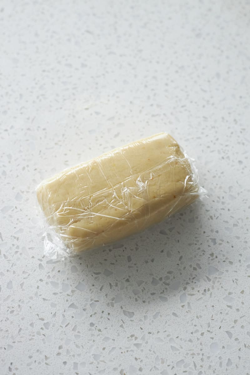 Cookie dough wrapped in plastic wrap for chilling.