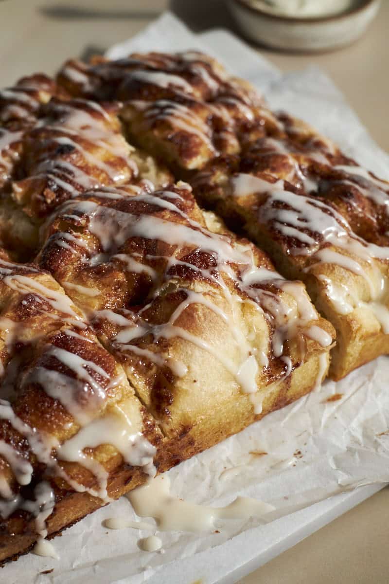 A side view of the frosting dripping on the Sourdough Discard Cinnamon Roll Focaccia.