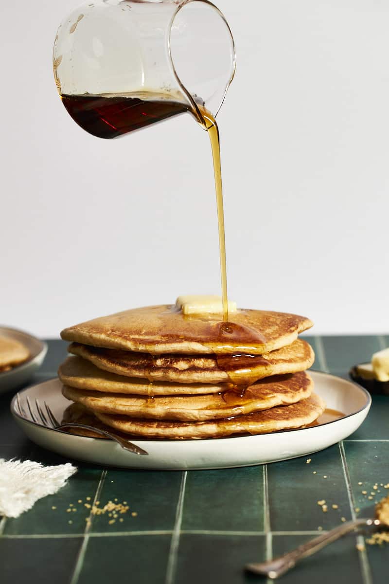 Maple syrup pouring onto a stack of Sourdough Discard Pancakes.