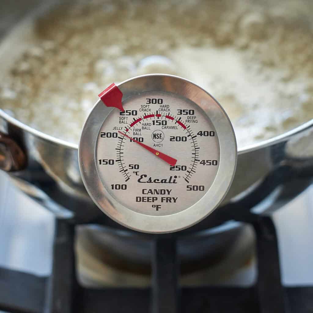 A candy thermometer on the edge of a pan.