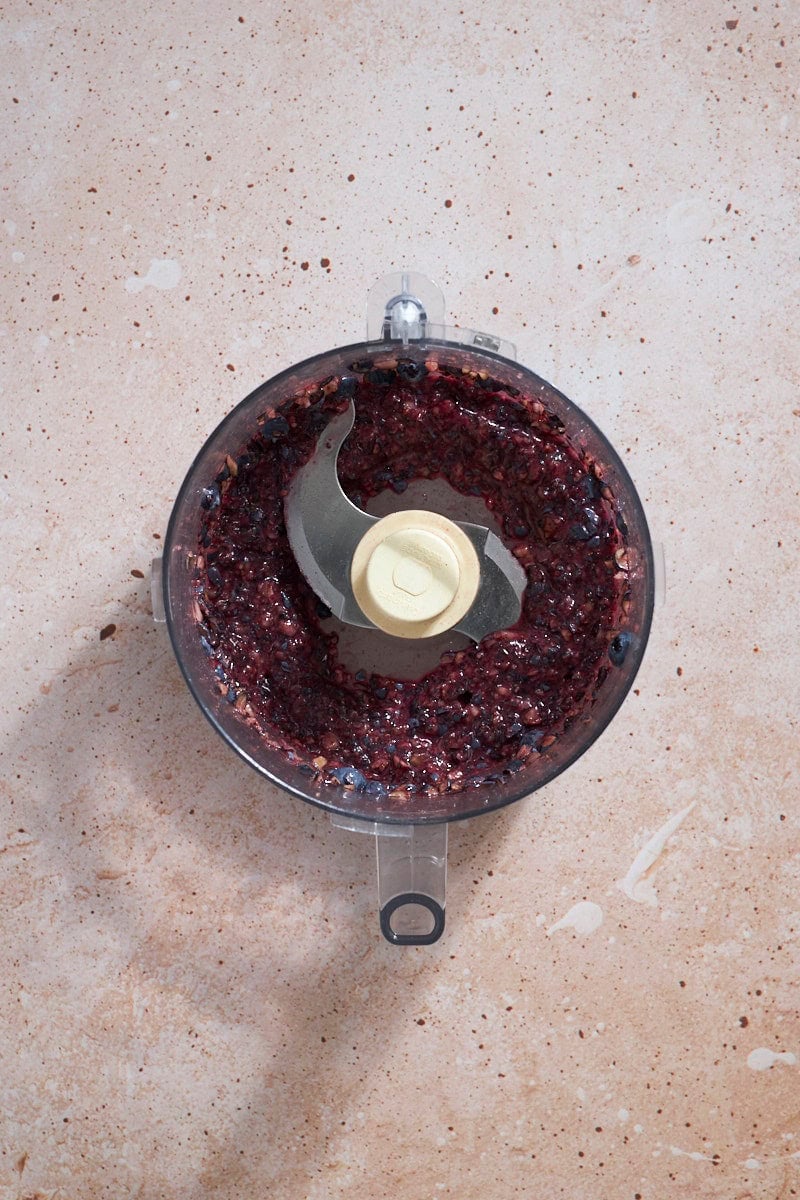 Crushed berries in the bowl of a food processor.