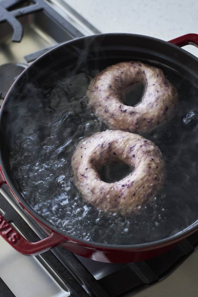Bagels boiling in a pot of water.