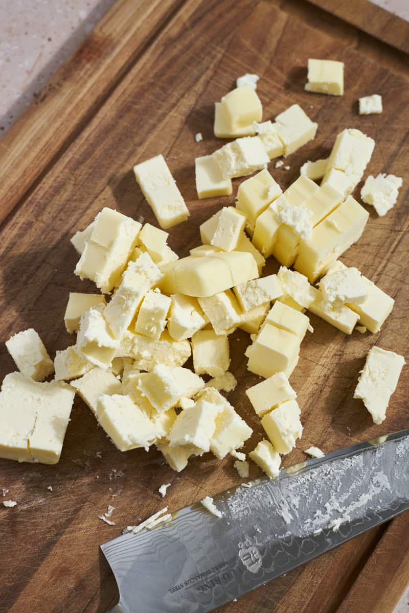 Cubed butter on a wooden cutting board.