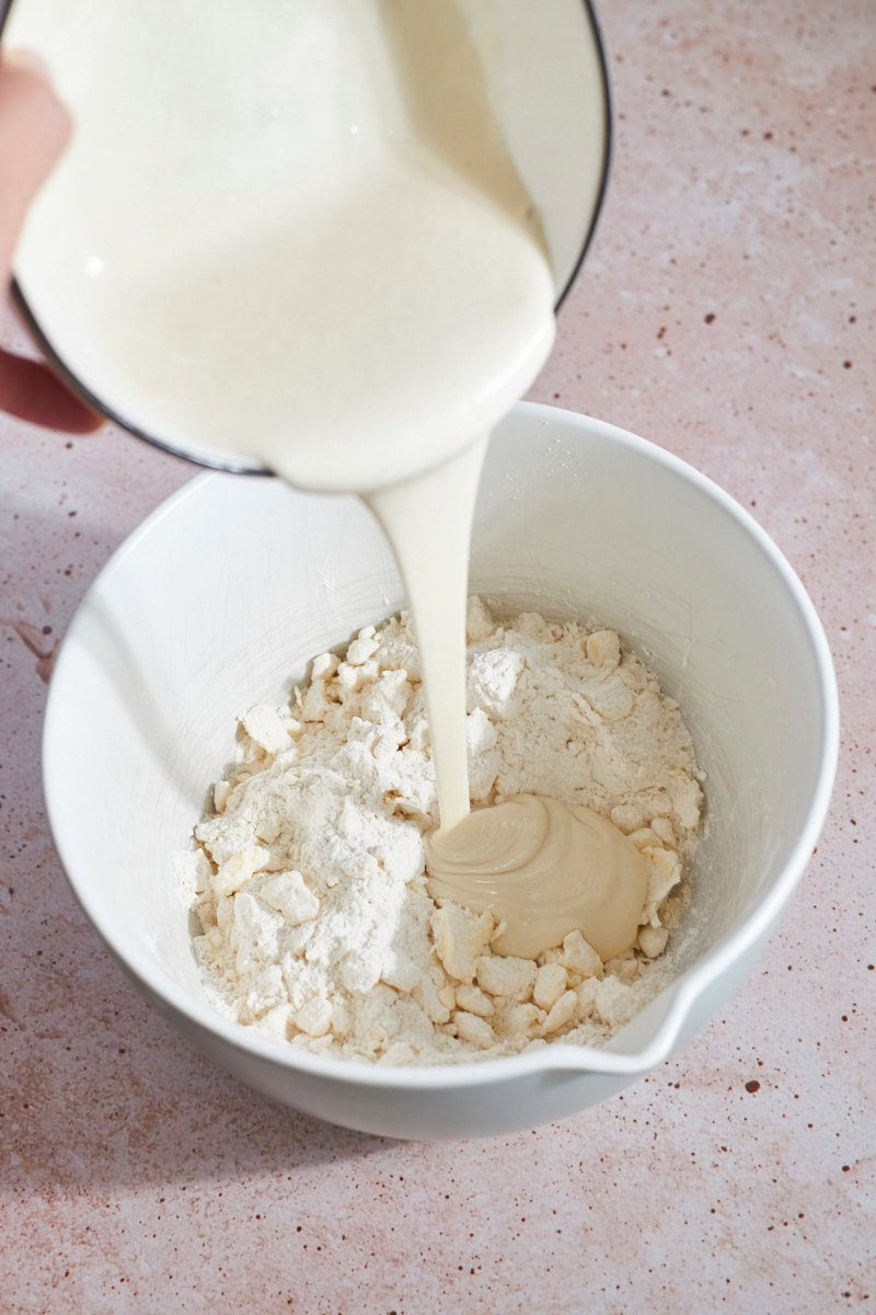 Sourdough discard mixture being poured into the mixing bowl.