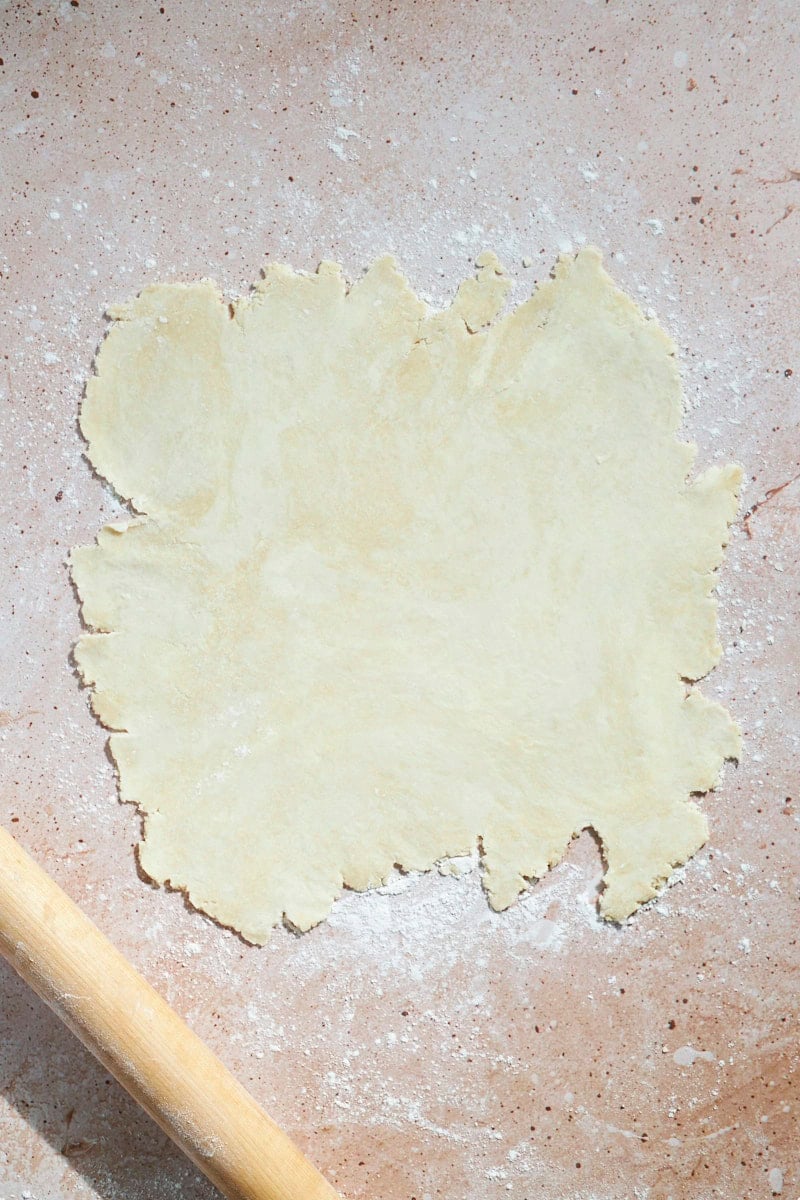 Crust rolled into a rough circle on a work surface.