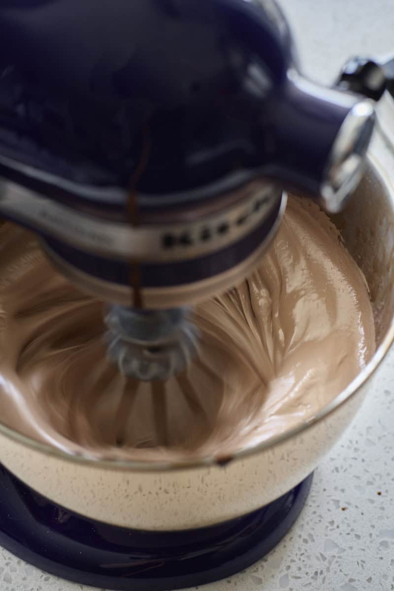 Marshmallow being whipped in the bowl of a stand mixer.