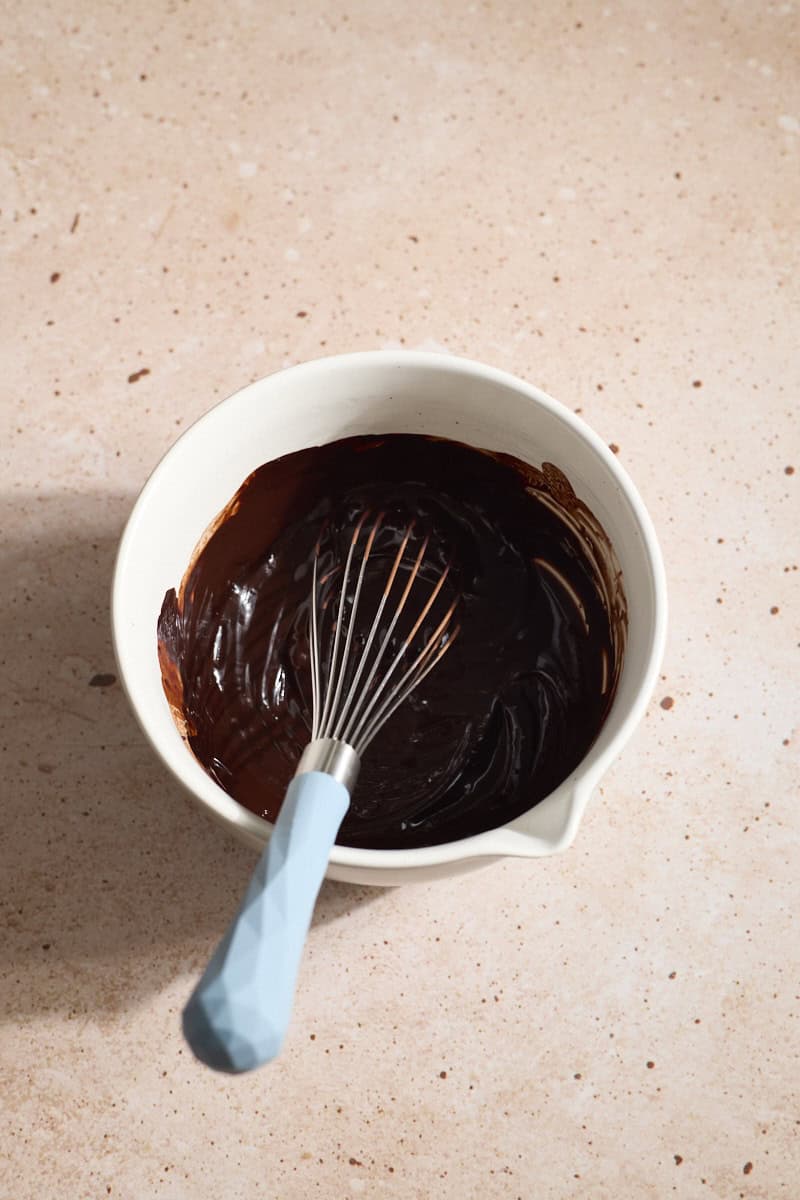 Chocolate mixture in a small bowl with a whisk.