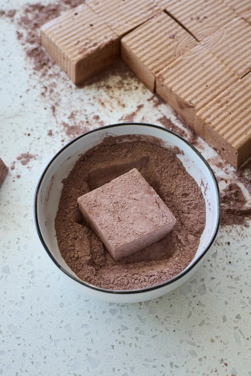 Marshmallow being rolled in the powdered sugar mixture.