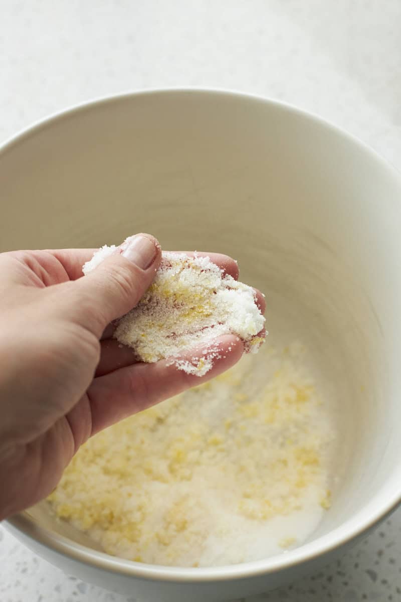 Sugar and lemon zest being pressed together.